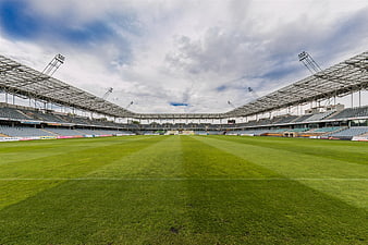Wide angle view of empty football stadium with green grass pitch