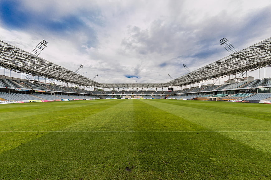 Wide angle view of empty football stadium with green grass pitch