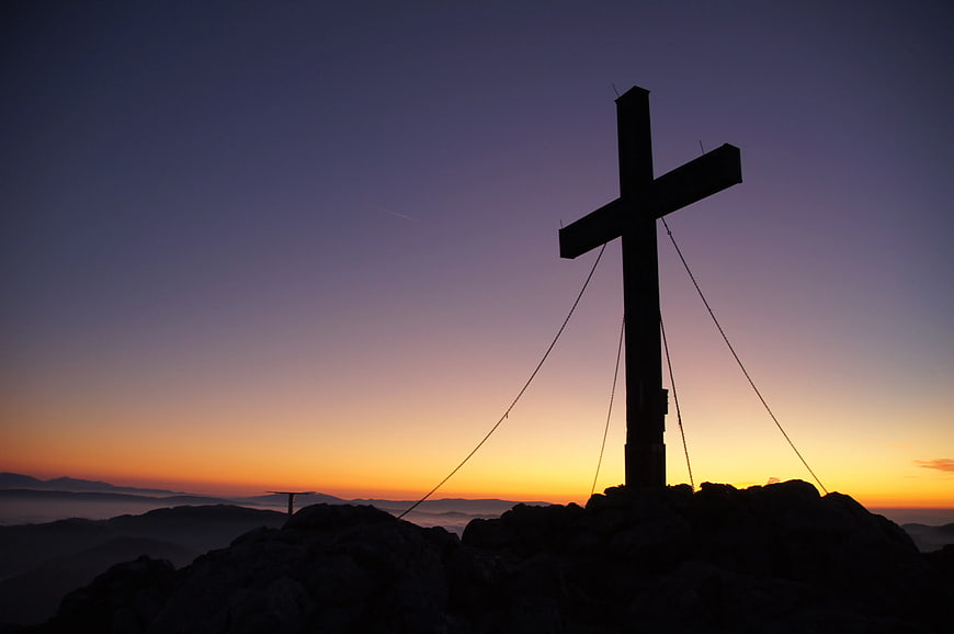 Silhouette of Cross on Mountain Peak at Sunset