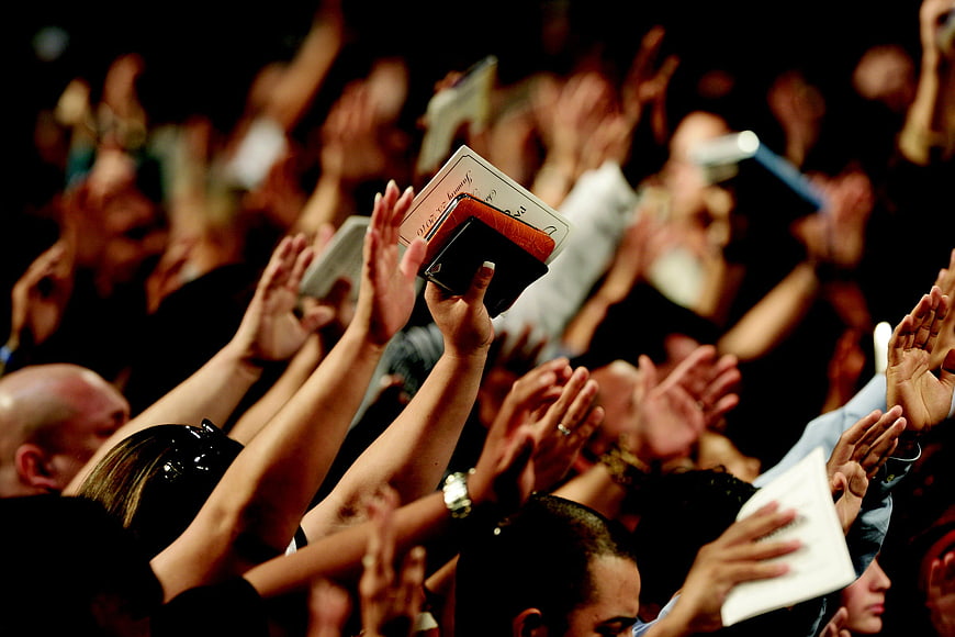 Crowd holding Bibles and hands raised in worship