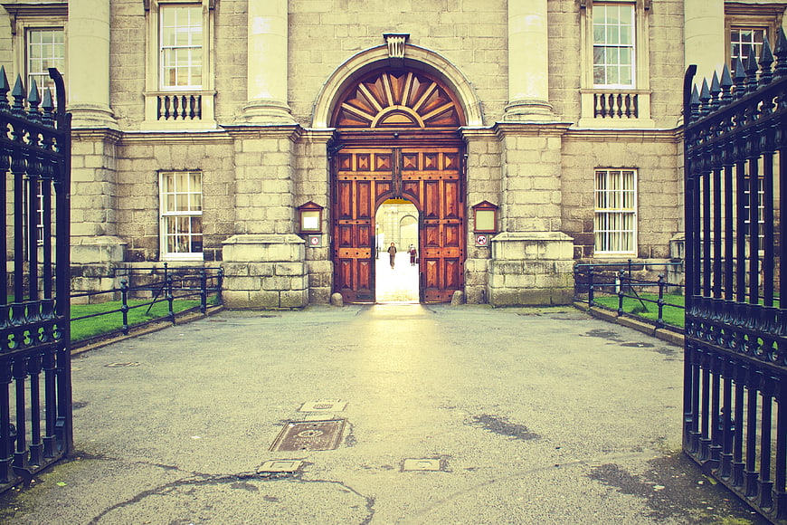 Historic Stone University Entrance With Grand Wooden Doors And Iron Gates