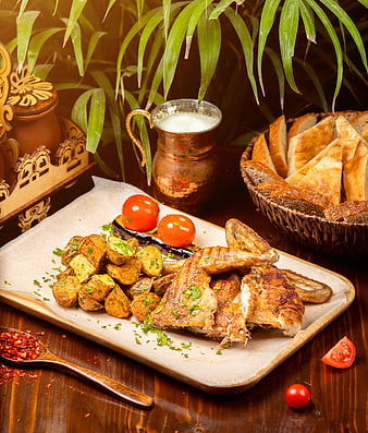 Grilled chicken with potatoes, bread, and ayran on rustic table