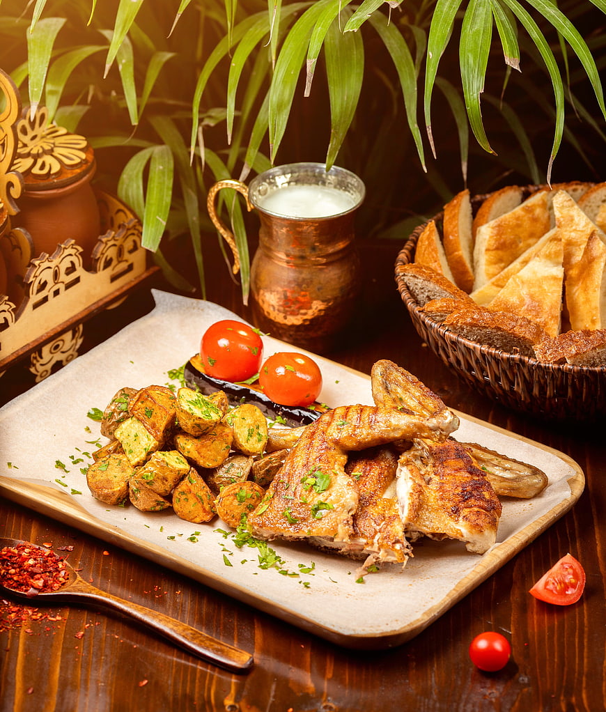 Grilled chicken with potatoes, bread, and ayran on rustic table
