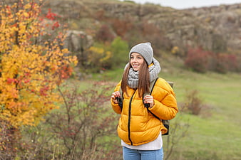 Happy female hiker in yellow jacket walking in autumn forest