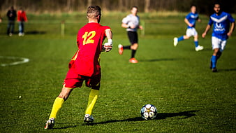Soccer player in red jersey kicking ball on grass field