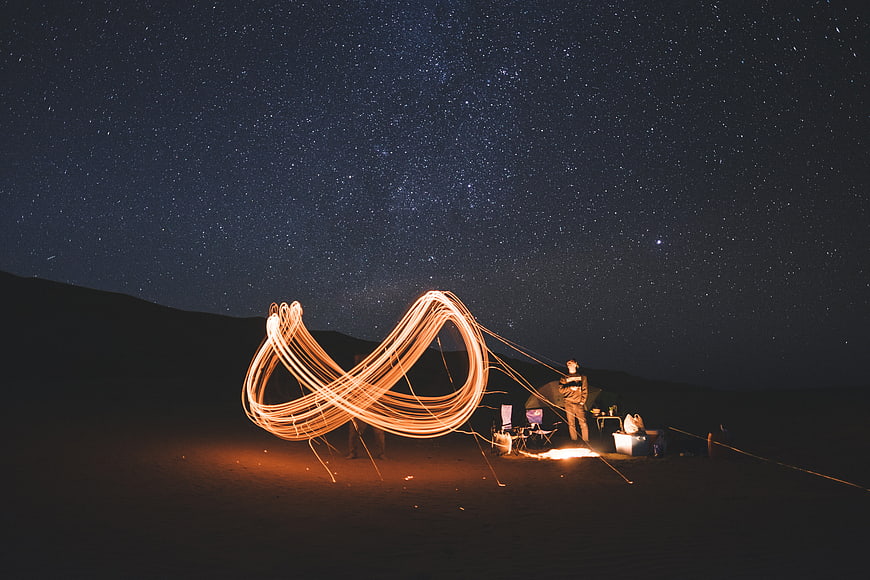 Light painting infinity symbol camping under starry night sky