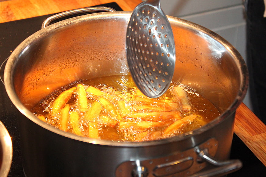 French Fries Deep Frying In Stainless Steel Pot With Slotted Spoon