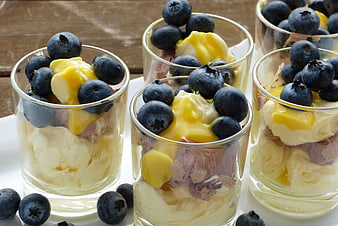Blueberry and cream dessert cups on a wooden table