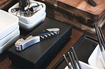 Modern Corkscrew on Black Box with Kitchen Utensils