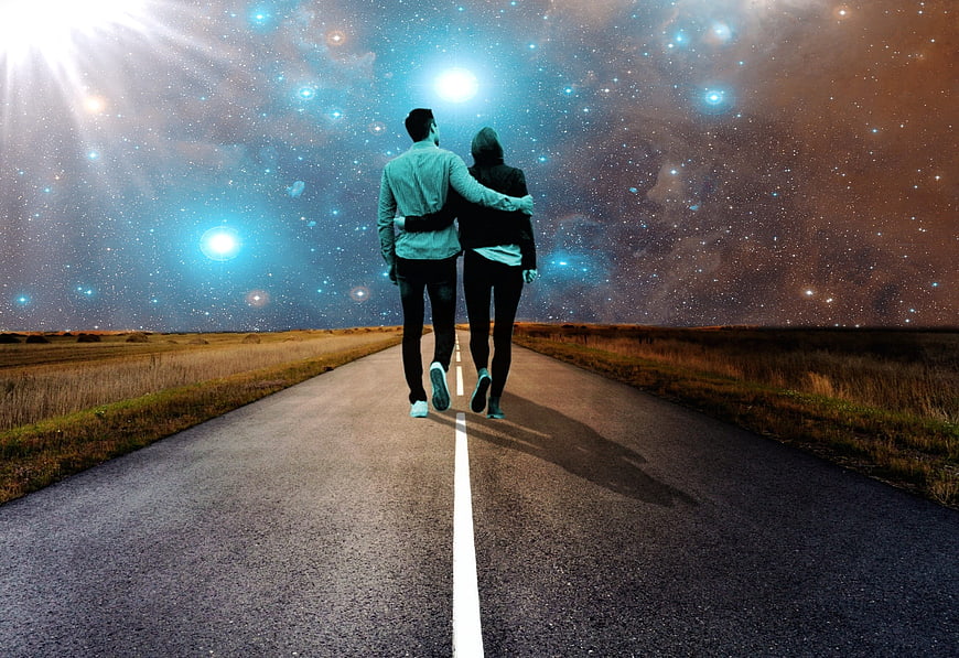 Couple walking down road under starry galaxy sky