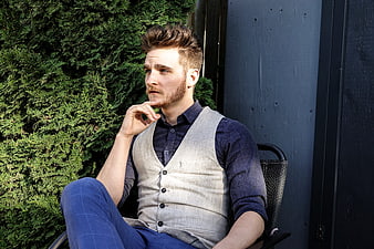 Stylish Bearded Man in Vest Sitting Outdoors