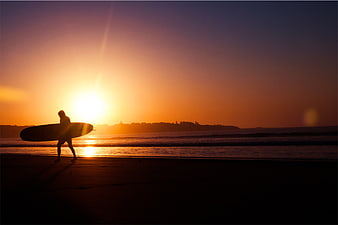 Silhouette of Surfer Walking on Beach at Sunset