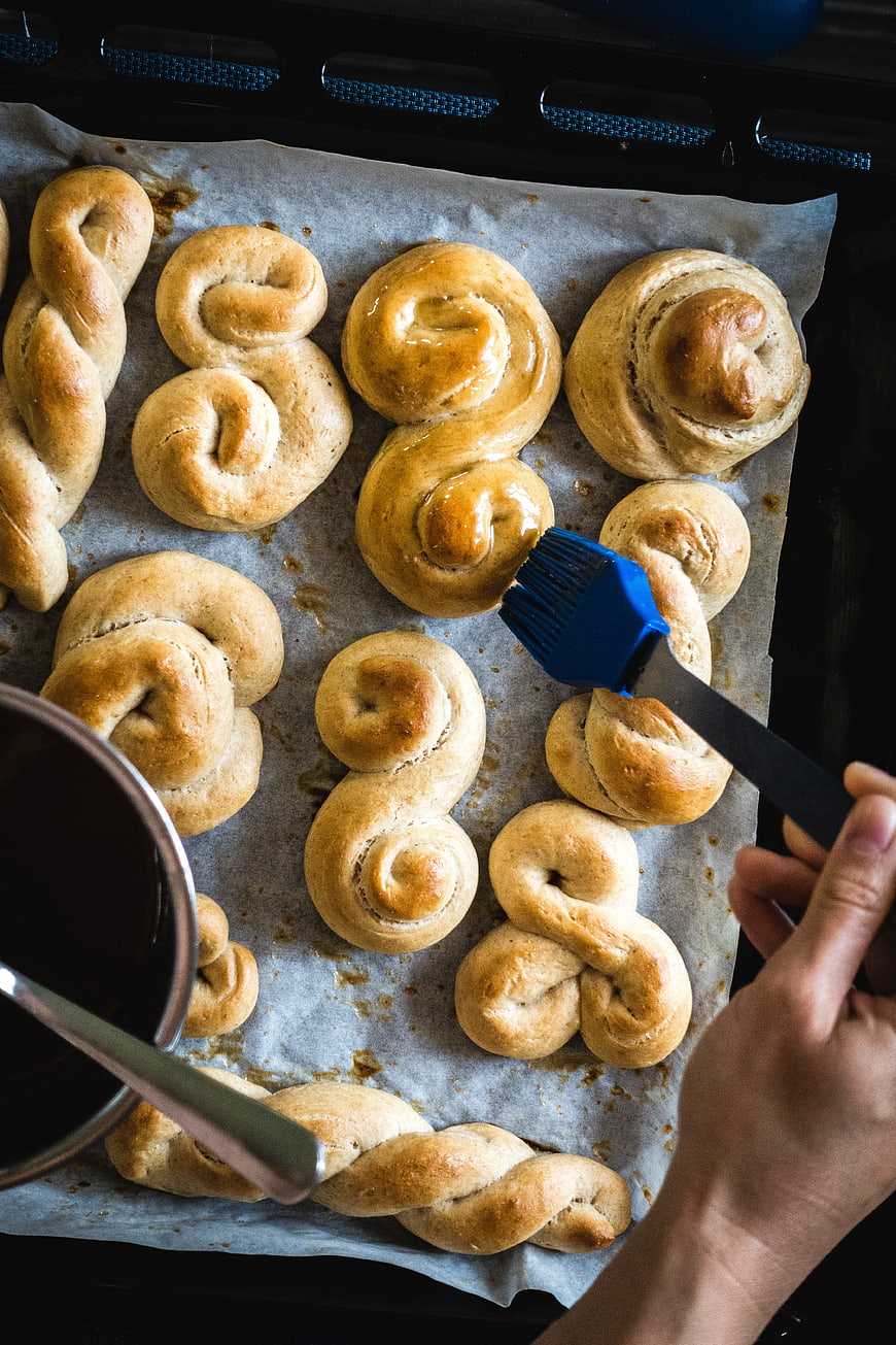 Top view of hand brushing glaze on fresh baked bread rolls