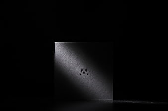 Minimalist black box with letter M in dramatic lighting