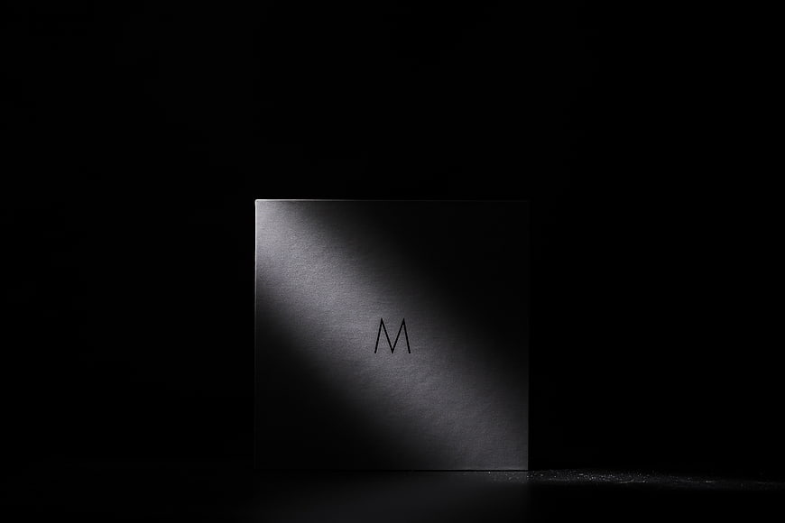 Minimalist black box with letter M in dramatic lighting