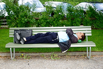 Tired business man sleeping on park bench with briefcase