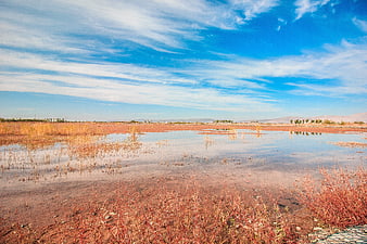 Red salt lake landscape with blue sky and clouds