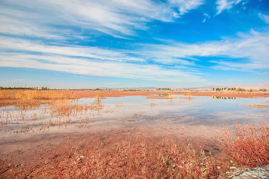 Red salt lake landscape with blue sky and clouds