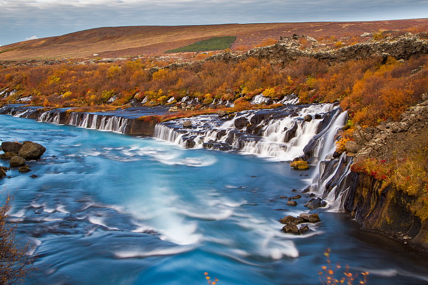Autumn waterfall landscape with blue river and orange foliage