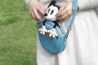 Woman holding blue bag with Mickey Mouse plush toy
