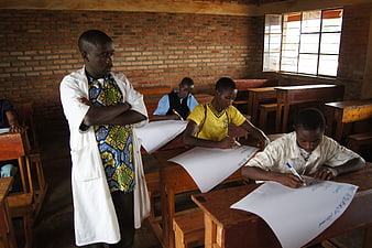 Teacher supervising students writing in a classroom