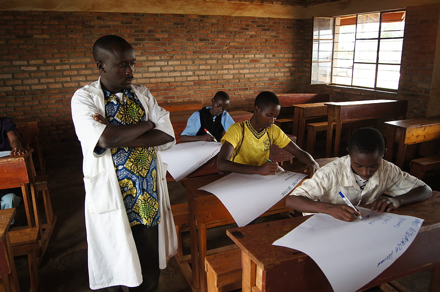 Teacher supervising students writing in a classroom