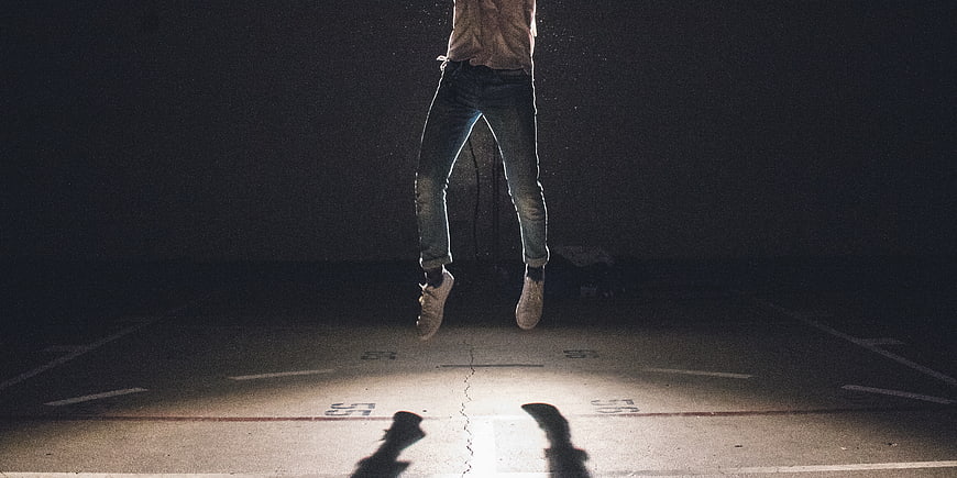 Man Jumping in Spotlight on Concrete Parking Lot