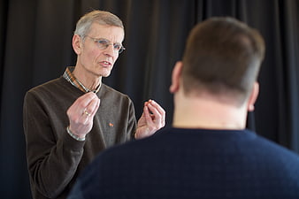 Senior man explaining concept to colleague in dark room