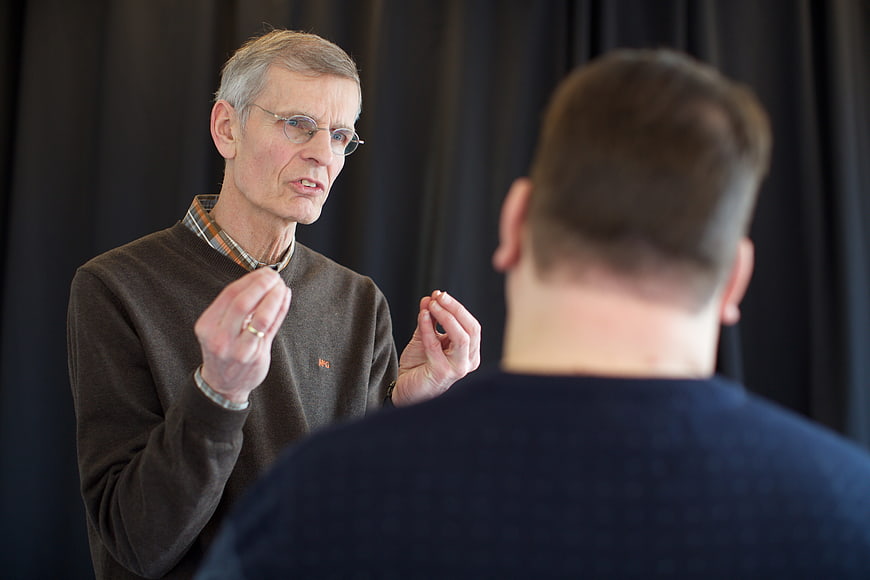 Senior man explaining concept to colleague in dark room