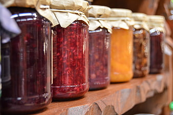 Homemade fruit jams in glass jars on rustic wooden shelf