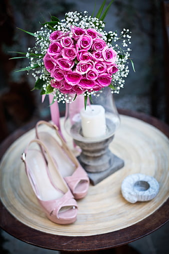 Pink bridal bouquet and shoes on rustic wooden table