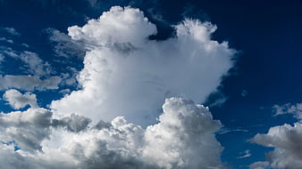 Dramatic white cumulus clouds against deep blue sky
