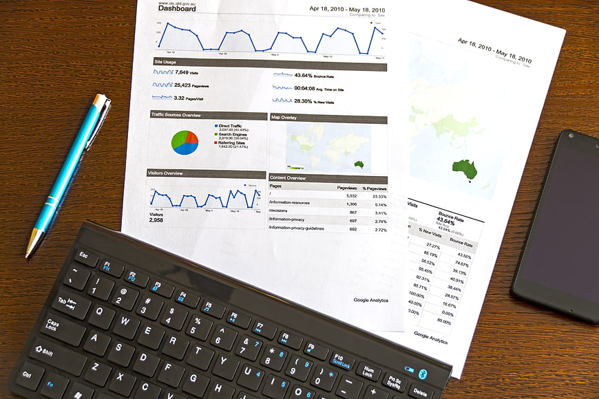 Printed Google Analytics Dashboard Report On Desk With Keyboard And Smartphone