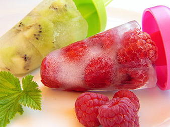 Homemade fruit popsicles with raspberries and kiwi on white plate