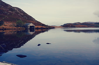 Serene Scottish Loch with Boathouse and Mountain Reflections