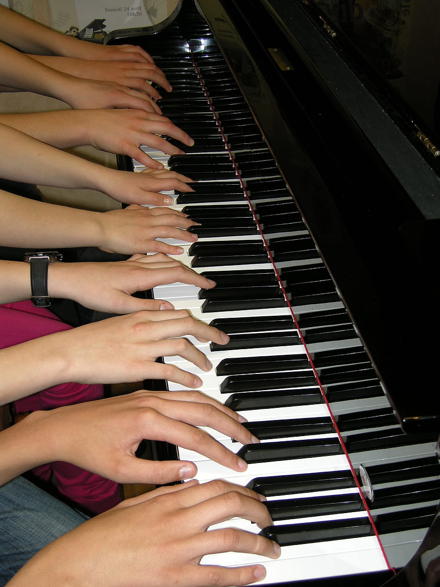 Multiple Hands Playing Piano Keys Together