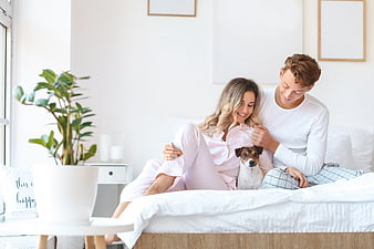 Happy young couple relaxing in bed with their dog