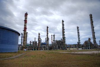 Wide industrial refinery complex with tall towers and blue storage tank