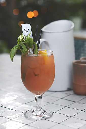 Refreshing Orange Cocktail with Basil Garnish on Tiled Table