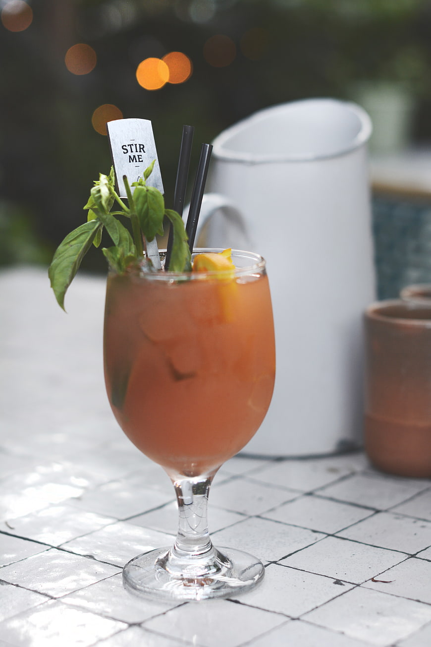 Refreshing Orange Cocktail with Basil Garnish on Tiled Table
