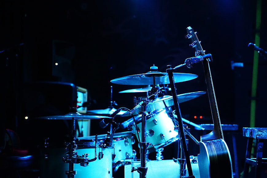 Drum Kit And Bass Guitar On Stage Under Blue Lighting