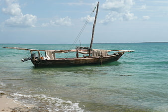 Traditional wooden dhow boat anchored in turquoise Zanzibar waters