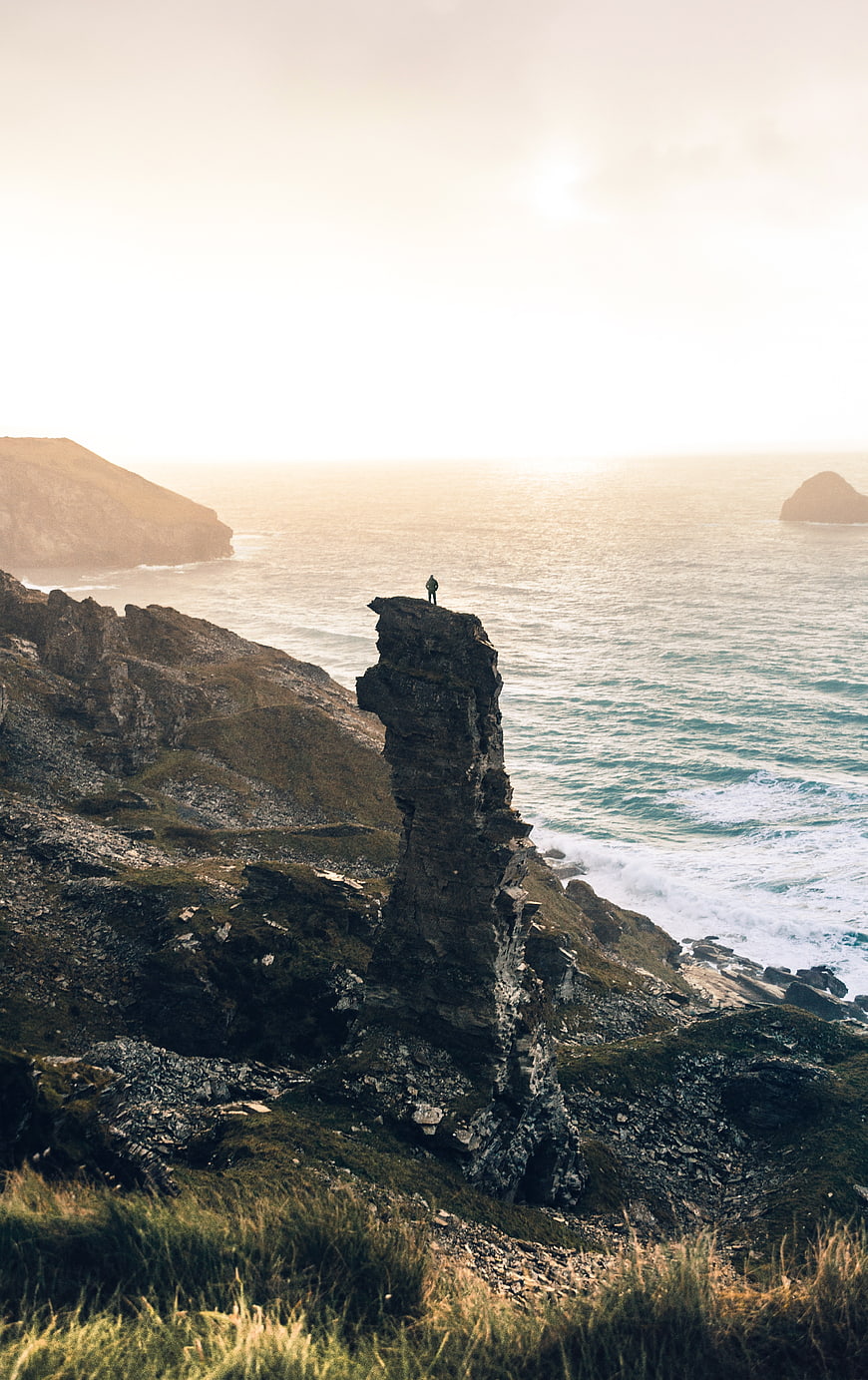 Lone Hiker Standing on Dramatic Coastal Rock Formation