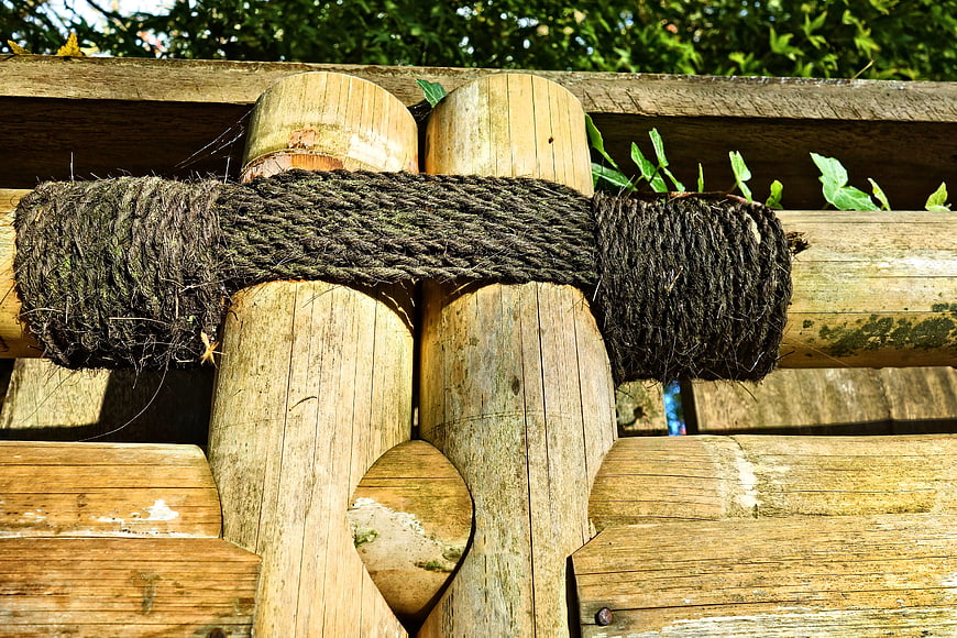 Close-up of weathered bamboo fence with thick rope tie