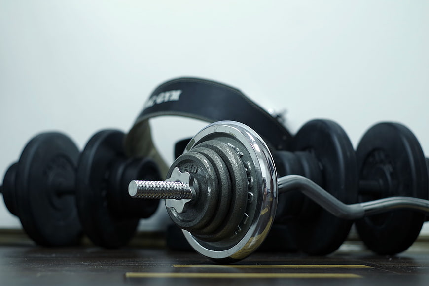 Close-up of gym dumbbells and weightlifting belt on floor