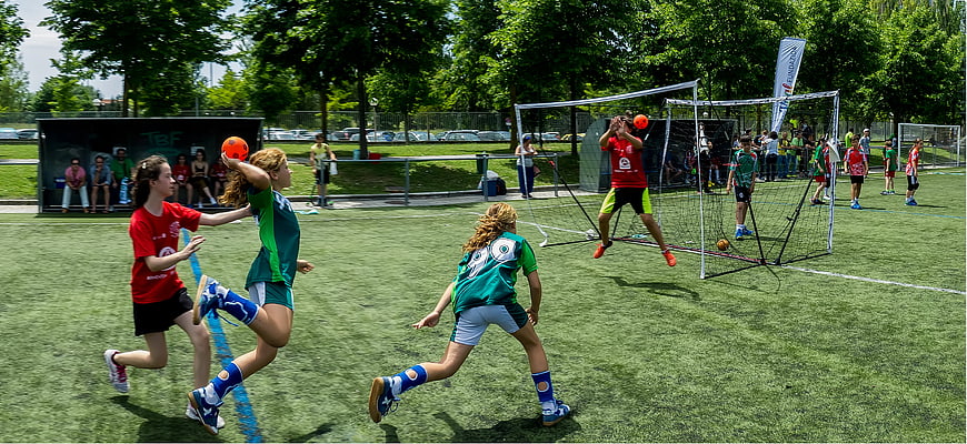 Young girls playing handball on outdoor artificial turf field