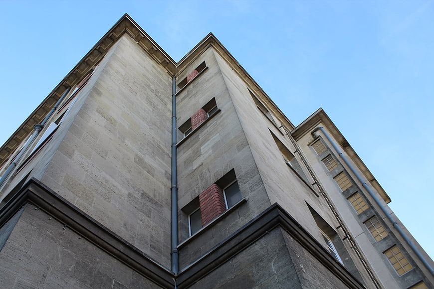 Low angle view of modern stone building facade against blue sky