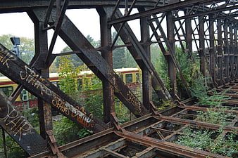 Rusty steel bridge structure with graffiti and passing train