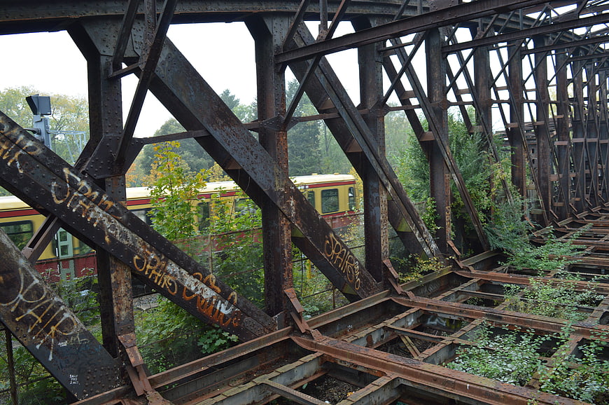 Rusty steel bridge structure with graffiti and passing train