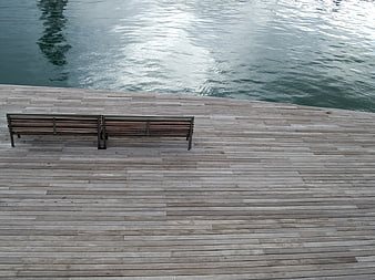 Empty wooden bench on waterfront boardwalk with rippling water